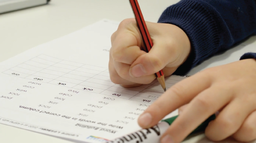 Student writing answers on a piece of paper