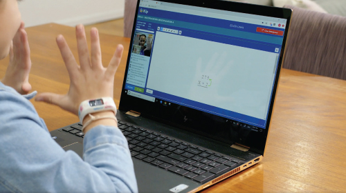 Student waving while working on computer